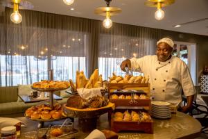 un chef parado frente a una mesa con pastas en Hotel Cardoso en Maputo