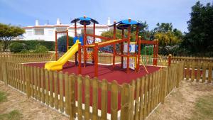 un parque infantil con un tobogán frente a una valla de madera en Quinta Das Figueirinhas & Quintinha Village en Armação de Pêra