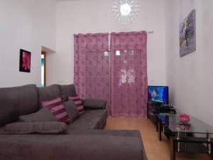 uma sala de estar com um sofá e uma cortina rosa em 2-bedroom Villa with pool em Torre-Pacheco