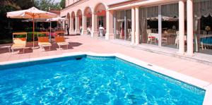 una piscina con sedie e un ombrellone accanto a un edificio di Hotel De La Paix a Lugano