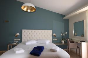 a bedroom with a large white bed with blue walls at Viaros Hotel Apartments in Tolo