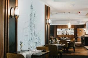 a restaurant with tables and chairs and a drawing on the wall at Focus Hotel Premium Kraków in Krakow