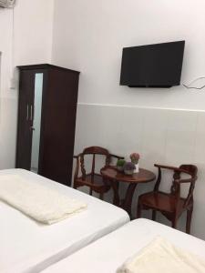 a bedroom with two beds and a flat screen tv at Nhà nghỉ Hoàng Huân in Long Xuyên