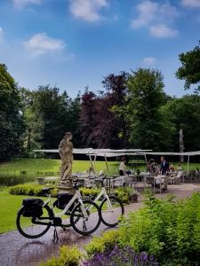 zwei Fahrräder, die neben einer Statue in einem Park geparkt sind in der Unterkunft Parc Broekhuizen l Culinair landgoed in Leersum