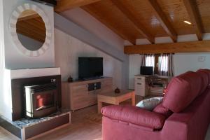 Una sala de estar con un sofá rojo y una chimenea. en Alojamiento Rural Abuela Andrea, en Molinilla