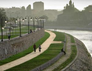 a group of people walking along a path next to the water at Glorious Rooms in Niš