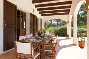 a dining room with a table and chairs on a patio at Casa con jardín y piscina - MORELL ONZE in Cala Morell