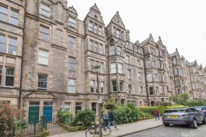 een groot bakstenen gebouw met auto's geparkeerd voor het bij 3 bed overlooking meadows park in Edinburgh