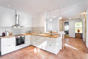 a kitchen with white cabinets and a brown tile floor at Can Terrats in Blanes