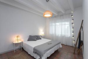 a white bedroom with a bed and a window at Can Terrats in Blanes