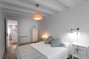 a white bedroom with a white bed and a lamp at Can Terrats in Blanes