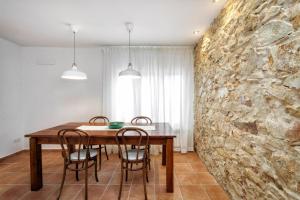 a dining room with a stone wall and a table and chairs at Can Terrats in Blanes