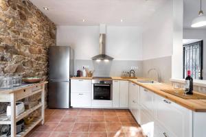 a kitchen with white cabinets and a stone wall at Can Terrats in Blanes