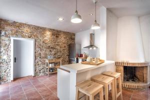 a kitchen with a counter and chairs and a fireplace at Can Terrats in Blanes +15 photos