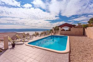 a swimming pool on a patio with chairs and a table at VILLA MASLINA, with private 32m2Pool, panoramic views on 100km coastline, 12 pax in Lokva Rogoznica