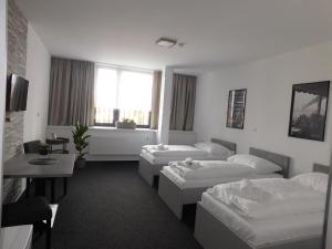 una camera d'albergo con tre letti e un tavolo di Penzion Nový Štěpánov a Valašské Meziříčí