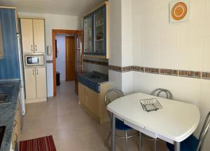 eine kleine Küche mit einem weißen Tisch und Stühlen in der Unterkunft Apartamentos San Miguel 2 in Almerimar