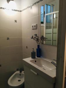 een badkamer met een wastafel, een toilet en een spiegel bij Casa Maria in Rota