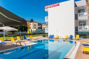 a swimming pool with chairs and a building at Vagelis Apartments Malia in Malia