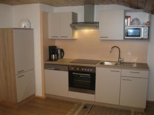 uma cozinha com armários brancos, um lavatório e um fogão em Rossruckhof em Rohrberg