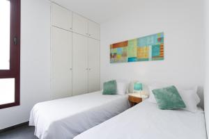 2 camas en una habitación con paredes blancas en Living Las Canteras Homes - LAS CANTERAS PENTHOUSE, en Las Palmas de Gran Canaria