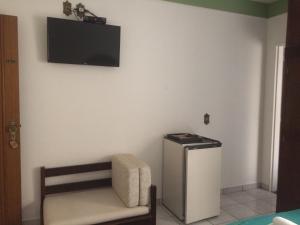 Habitación con silla y TV en la pared. en Pousada Aguas de Ibira, en Termas do Ibirá