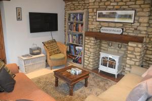 ein Wohnzimmer mit einem Steinkamin und einem TV in der Unterkunft Church Cottage Barn in Longborough + 22 Fotos