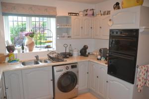 eine Küche mit Waschmaschine und Spüle in der Unterkunft Church Cottage Barn in Longborough