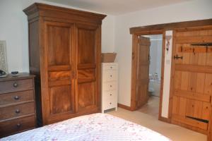 ein Schlafzimmer mit einem Bett, einer Kommode und einem Schrank in der Unterkunft Church Cottage Barn in Longborough