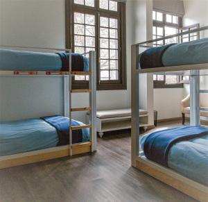 um quarto com 3 beliches com lençóis azuis em Pariwana Hostel Santiago em Santiago
