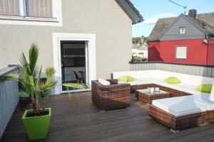 a patio with a couch and chairs on a deck at Feriendomizil "Alte Post" II in Pronsfeld