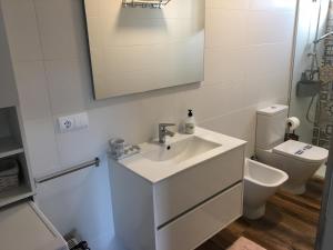 a white bathroom with a sink and a toilet at Casa apartamento a pie de playa Areabrava - en Cangas - Hio -Galicia- España in Hio