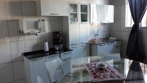 a kitchen with a glass table and white cabinets at Edifício Belio in Cascavel