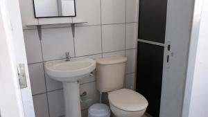 a white bathroom with a toilet and a sink at Edifício Belio in Cascavel +7 photos