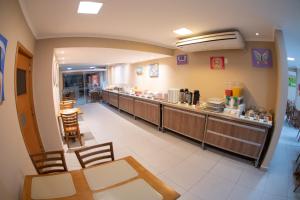 a restaurant with a long counter with chairs and a buffet at Getúllio Hotel in Cuiabá