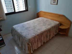 ein Schlafzimmer mit einem Bett mit einem Kopfteil aus Holz in der Unterkunft Apartamento para 6 pessoas a 10m da praia in Praia Grande