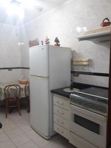 eine Küche mit einem weißen Kühlschrank und einem Herd in der Unterkunft Apartamento para 6 pessoas a 10m da praia in Praia Grande