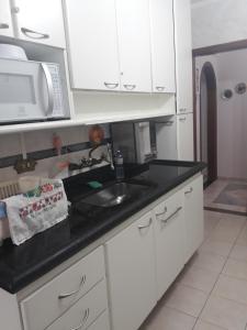 eine Küche mit einer Spüle und einer Mikrowelle in der Unterkunft Apartamento para 6 pessoas a 10m da praia in Praia Grande