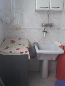 ein Badezimmer mit einem Waschbecken und einem Tisch mit Blumen darauf in der Unterkunft Apartamento para 6 pessoas a 10m da praia in Praia Grande