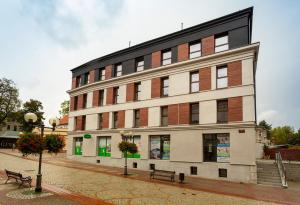 a building on a street with benches in front of it at Tymon Apartament przy deptaku in Szczawno-Zdrój