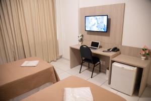 a hotel room with a desk with a laptop on it at Getúllio Hotel in Cuiabá