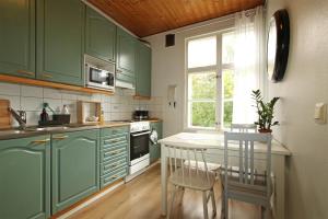 a kitchen with green cabinets and a table with chairs at Idyllic central wooden house apartment in Pori