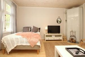 a bedroom with a bed and a flat screen tv at Idyllic central wooden house apartment in Pori