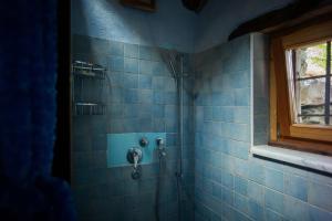 y baño con ducha de azulejos azules y ventana. en Redelnascht, en Gressoney-la-Trinité