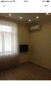 uma sala de estar com televisão e janela em Уютная квартира около станции метро em Yerevan