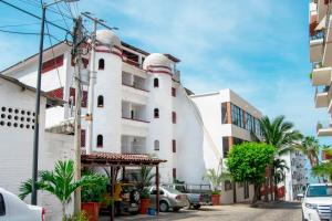 a white building with cars parked in front of it at Petit Hotel Pilitas in Puerto Vallarta