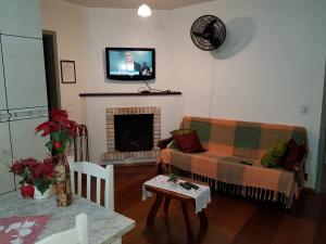 sala de estar con sofá y TV encima de la chimenea en Apartamento a DUAS quadras do Centro, en Gramado