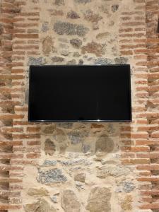 TV de pantalla plana en una pared de piedra en Santa Suites, en Ávila