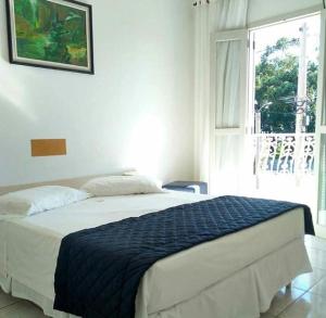 a bedroom with a large bed with a window at Hotel Muralha in São Lourenço do Sul