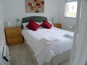 a bedroom with a large white bed with red pillows at Chalet for two - Dartmouth in Dartmouth